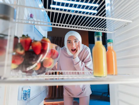 A lady looking at fruits and groceries in a fridge purchased through the Benefits of Easy Payment.