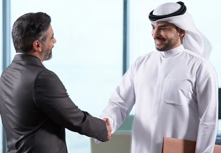business man wears black suit shakes hands with boubyan staff - رجل أعمال يلبس بدلة سوداء يصافح موظف بنك بوبيان