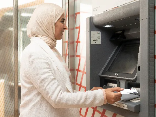 A woman using an ATM for accessing the Boubyan Deposit service