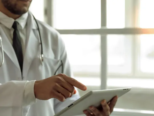 طبيب يُطّلع على iPad للحصول على معلومات حول باقة الأطباء من بنك بوبيان.